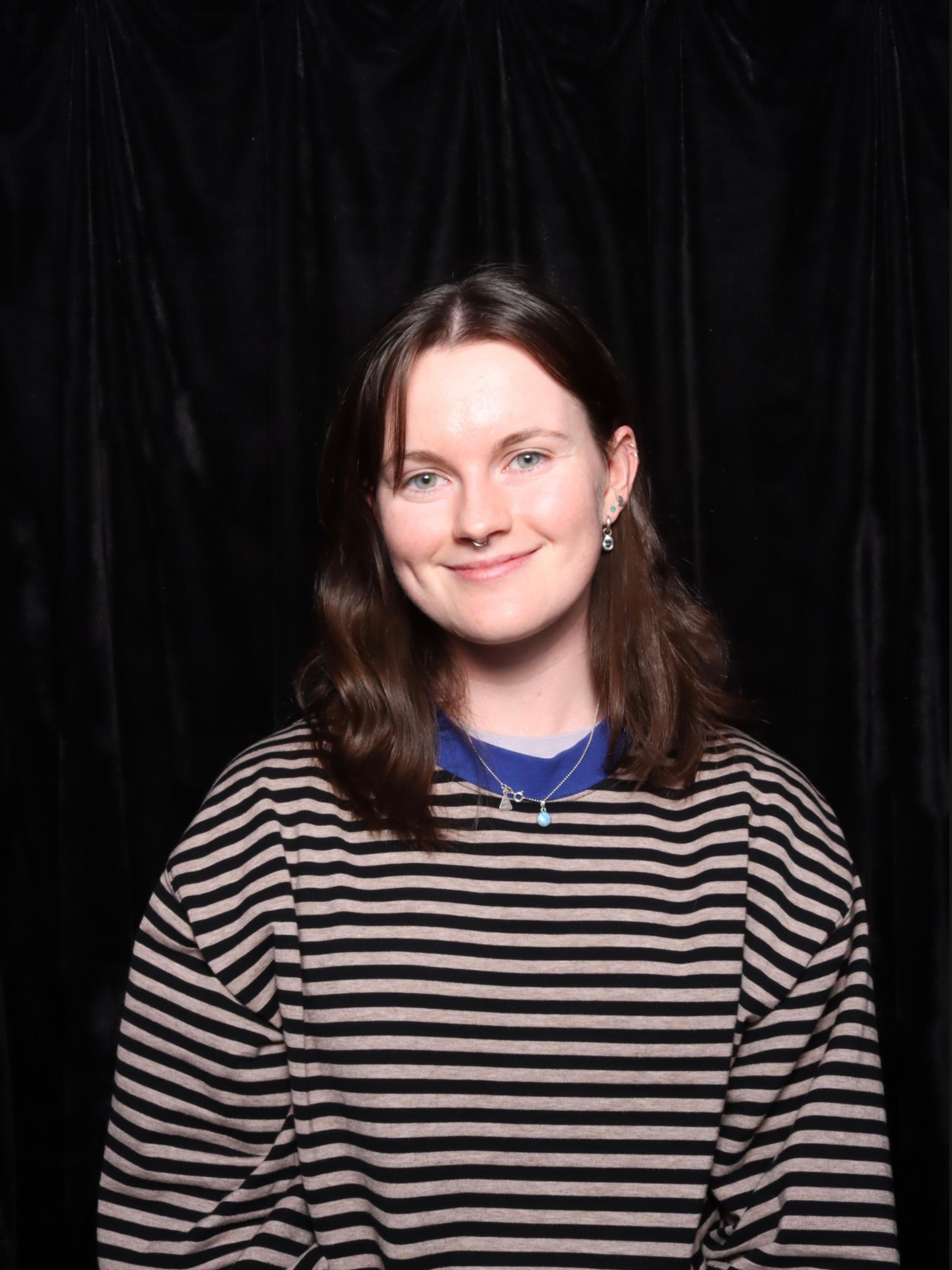 Headshot of artist & owner of Moyo Studio, Maya, on a black background.